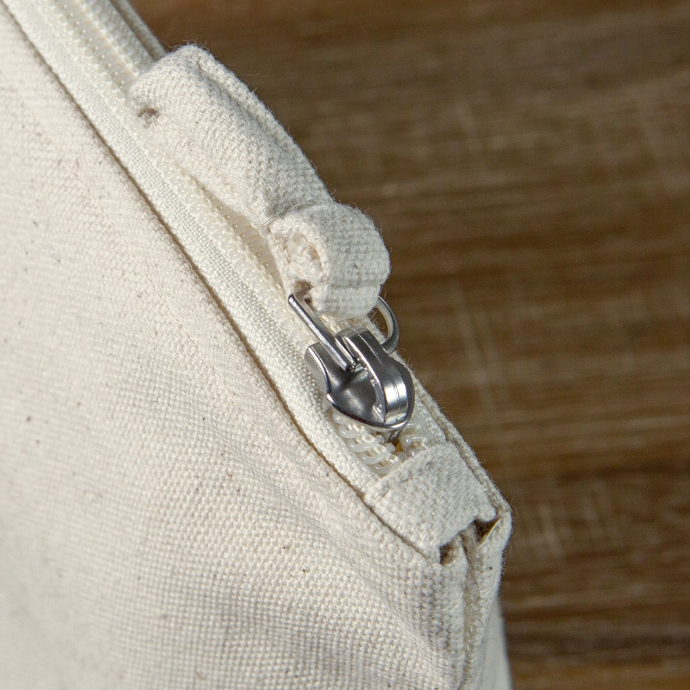 Detailaufnahme der naturfarbenen sapeco Kosmetiktasche aus Bio-Baumwolle mit Reißverschluss, Metallschieber und Stoffschlaufe.