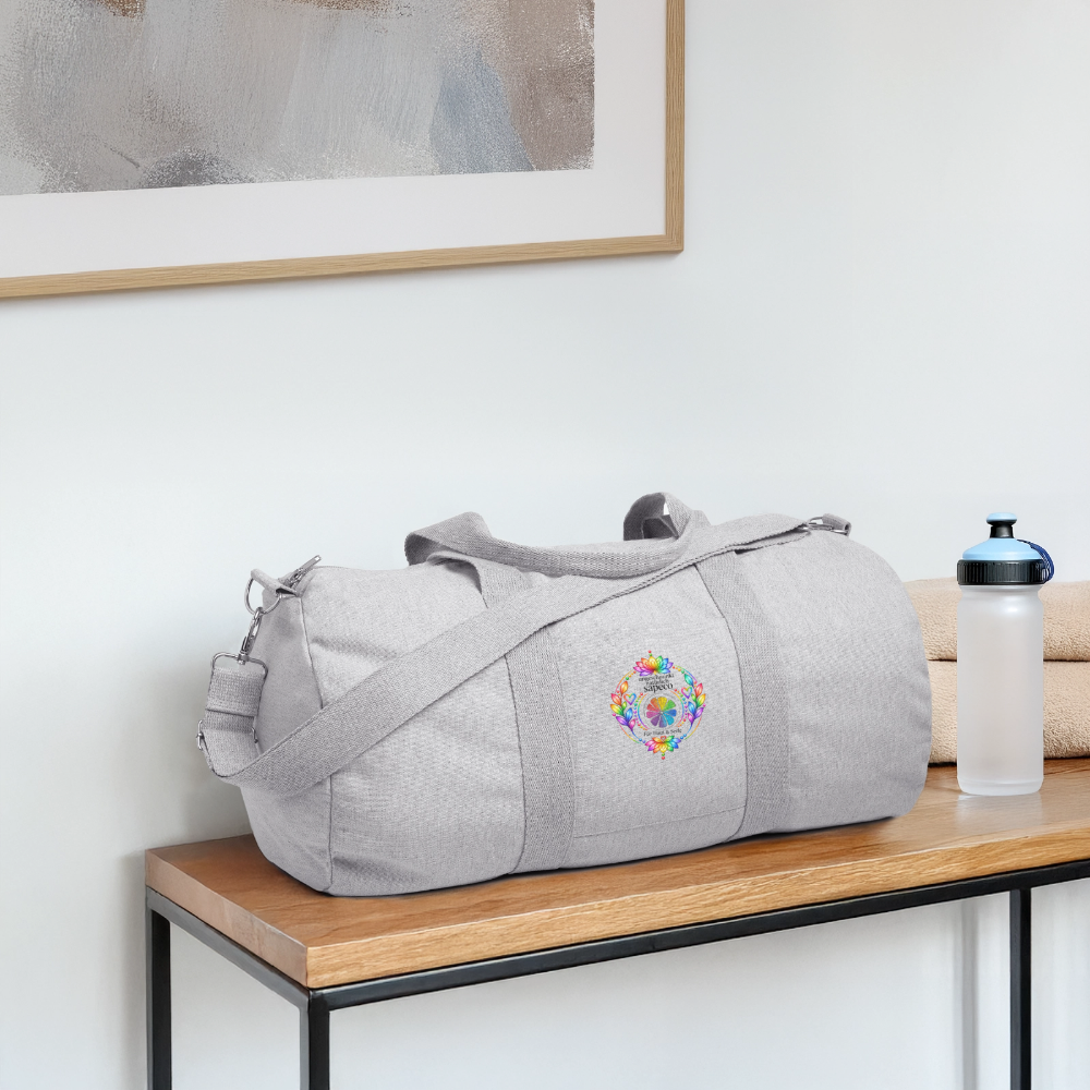 Graue Sporttasche aus recyceltem Canvas mit farbenfrohem Chakra-Motiv von ungeschminkt natürlich sapeco, dekorativ auf einer Bank präsentiert.